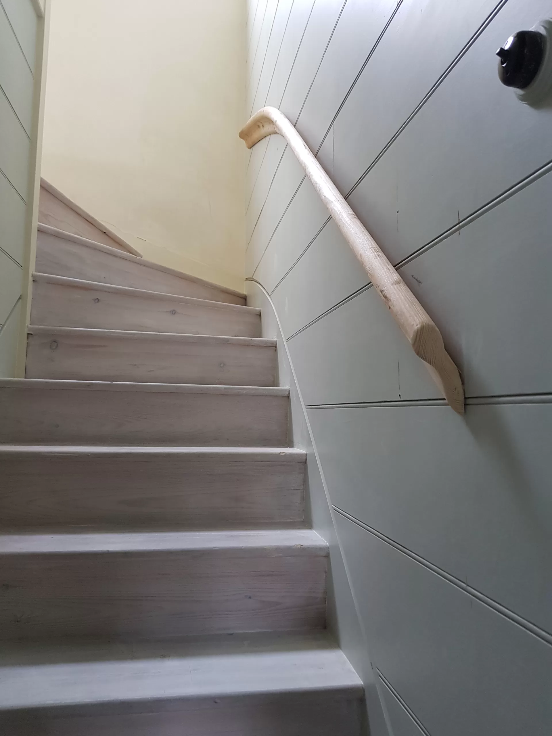 Finished staircase with panelling and curved handrail.